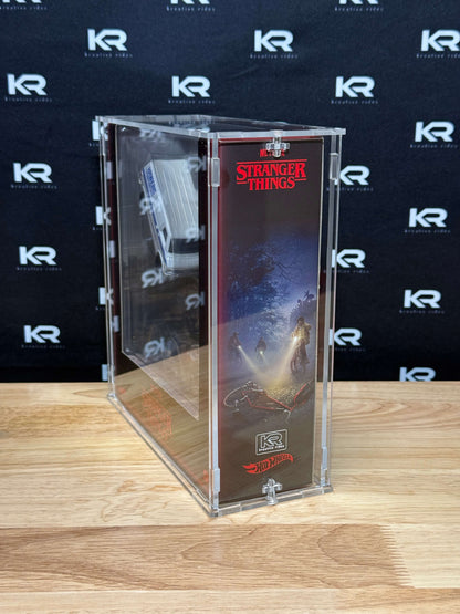 A clear acrylic display case containing a Stranger Things collectible figure, standing on a light wood tabletop against a black backdrop with repeated white KR logos.